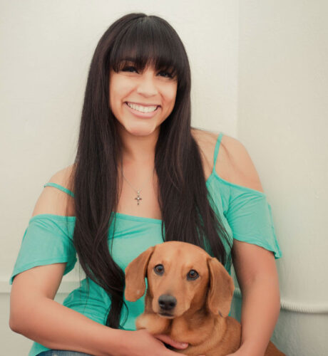 Carmel Mims with small brown cute dog on her lap.