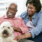 African American couple sitting with their dog with big smiles.
