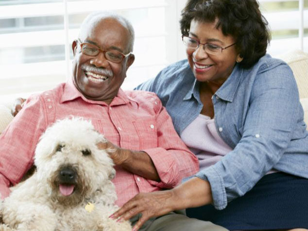 African American couple sitting with their dog with big smiles.