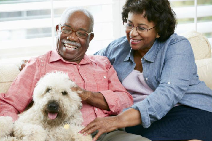 African American couple sitting with their dog with big smiles.