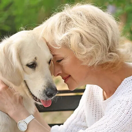 Elderly woman holding dog by his head with love.