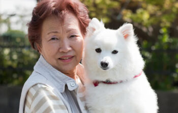 Asian woman holding a white dog.