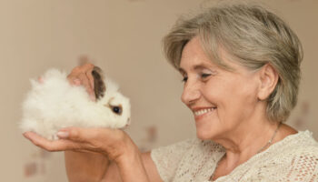 Happy senior woman holding a little white rabbit.