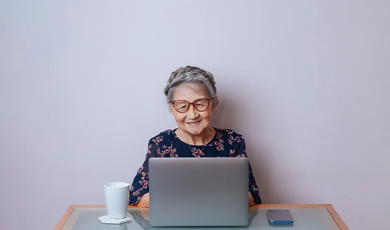 Senior woman sitting at a table with her laptop.