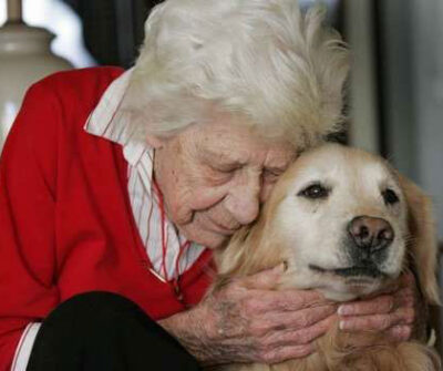 Senior woman hugging her dog close to his face.