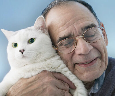Senior man hugging his cat close to his face.